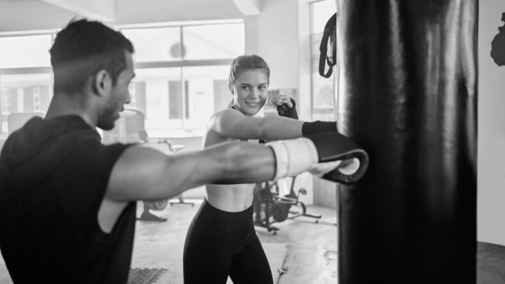 Entrenador haciendo un entrenamiento de fuerza para boxeo a una alumna