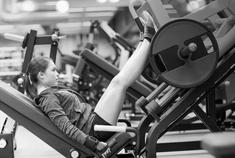 Mujer ejercitando las piernas en la máquina de prensa inclinada del gimnasio